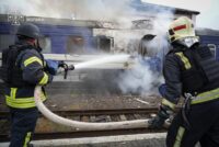 Dieses vom ukrainischen Katastrophenschutzdienst am 13. September 2026 veröffentlichte Foto zeigt Feuerwehrleute, die einen durch einen Drohnenangriff nahe der polnischen Grenze beschädigten Zugwaggon mit Wasser besprühen. (Foto: Ukrainischer Katastrophenschutzdienst / AFP)