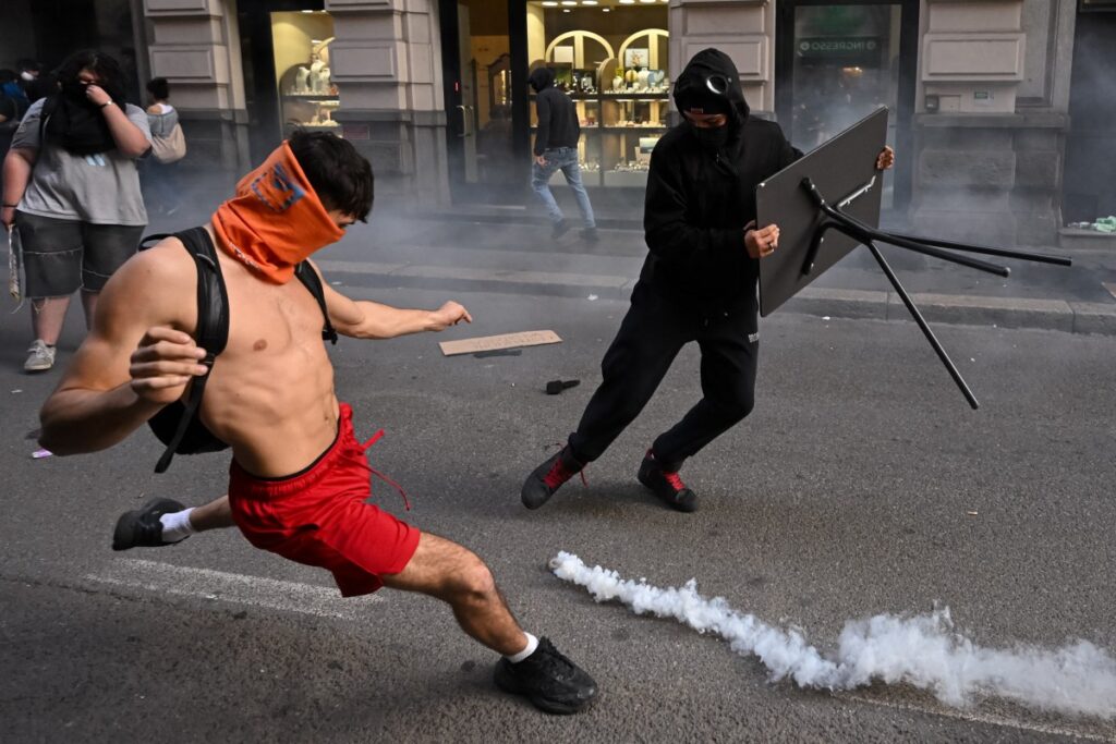 Ein Demonstrant tritt während Zusammenstößen mit der Polizei bei einer regierungsfeindlichen Demonstration der Bewegung „Italia in Piazza“ auf der Piazza Duomo in Mailand am 17. Oktober 2026 eine Tränengasgranate zurück. (Foto: Piero Cruciatti / AFP)