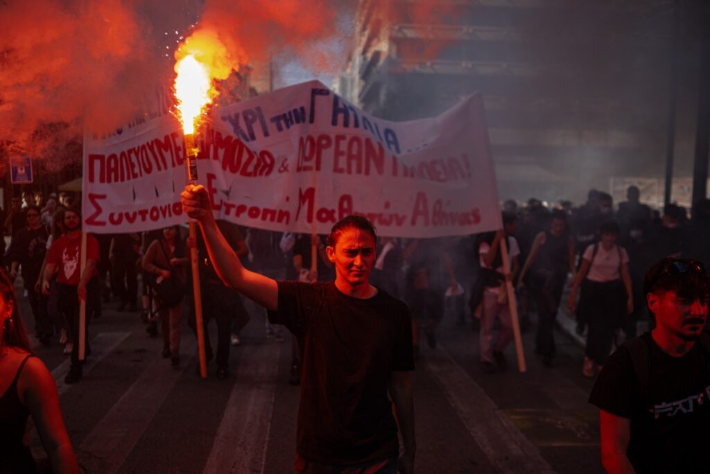 Ein Demonstrant hält eine Leuchtfackel in der Hand, während Studenten, Lehrer und Beamte an einer Kundgebung in Athen am 21. Oktober 2026 teilnehmen, um gegen die hohen Lebenshaltungskosten zu protestieren. (Foto: Angelos TZORTZINIS / AFP)